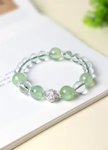 Detalle de una pulsera de cuentas de prehnita verde y cuarzo con dije de loto de plata