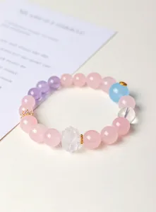Vue détaillée d'un bracelet en cristal rose et violet avec une perle lotus sculptée.