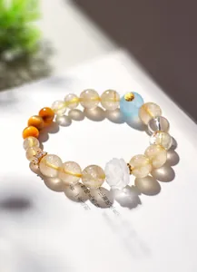 Détail d'un bracelet en quartz rutilé doré avec une perle de lotus en cristal blanc.