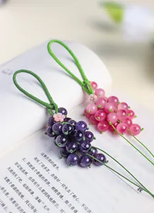 Detailed view of handmade purple and pink chalcedony grape pendants on an open book