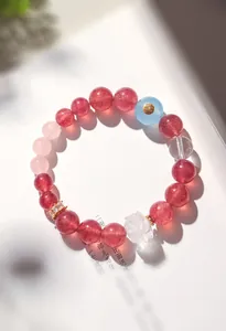 Gros plan d'un bracelet en quartz fraise avec une perle de lotus en cristal blanc