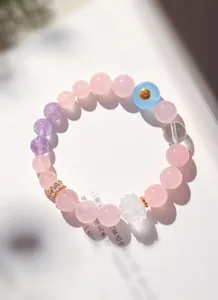 Gros plan d'un bracelet en perles avec des cristaux de lotus roses, violets et clairs.