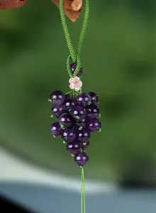 Macro close-up detail of a purple chalcedony grape pendant with green hand-woven cord