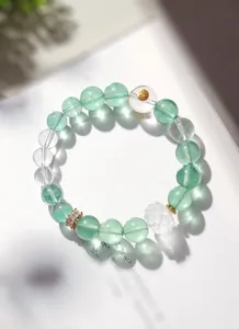 Détail macro du bracelet en fluorite verte et quartz clair avec lotus sculpté