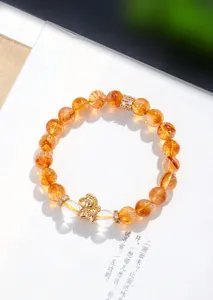 Dettaglio macro di un bracciale in quarzo rutilato dorato con ciondolo a cavallo