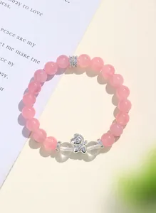 Vista dettagliata di un bracciale di perle in quarzo rosa con ciondolo a pony in argento e distanziali.