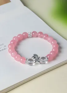 Primo piano di bracciale con perle di cristallo rosa e ciondolo a forma di cavallino.