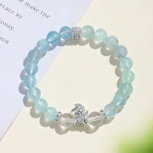 Elegante bracciale di perle di acquamarina con ciondolo a cavallo in argento su fondo beige