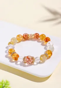 Detail view of a multi-gemstone crystal bracelet with rutilated quartz and gold spacers.