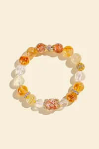 Macro view of yellow rutilated quartz bracelet with elegant gold-tone crystal accents