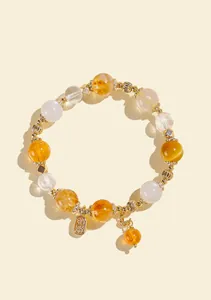 Macro detail of natural citrine and moonstone beaded bracelet with gold charm
