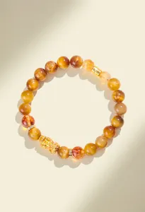 Detailed macro view of natural yellow tiger eye beads and golden Pixiu charm bracelet