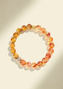 Close-up of a natural yellow quartz and golden tiger eye bracelet with a gold piyao charm