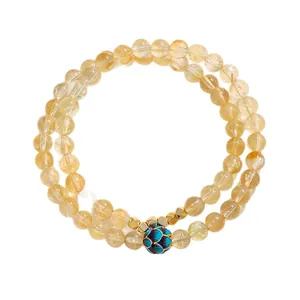 Pulsera de doble capa de citrino amarillo con un amuleto de flor en esmalte azul brillante.