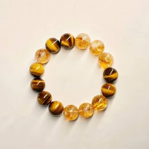 Nahaufnahme eines Armbands aus gelbem Citrin und Tigerauge-Perlen auf neutralem Grund