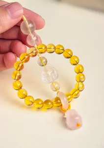 Detail shot of a natural citrine and rose quartz car charm featuring a fox carving