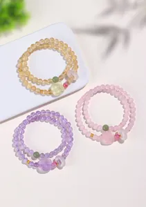 Trois bracelets en pierres fines colorées sur un plateau blanc avec des ombres douces.