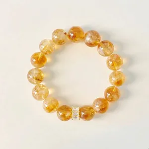 Nahaufnahme eines gelben Citrin-Perlenarmbands mit einem goldenen Kristall-Abstandshalter.