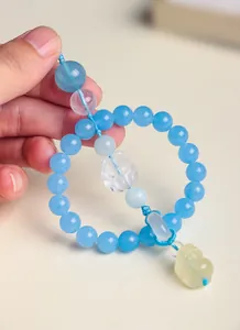 Close-up of blue crystal car charm with carved fox and yellow Pixiu pendant