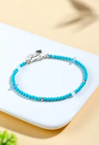 Close-up detail of natural turquoise and aquamarine beaded bracelet with silver heart charm.