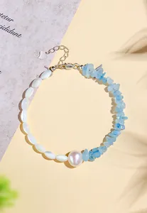 Close-up of aquamarine crystal and pearl bracelet on a sunny textured background