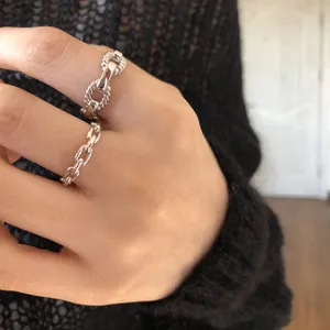 Detailed macro view of S925 sterling silver chain rings on a hand with black sweater