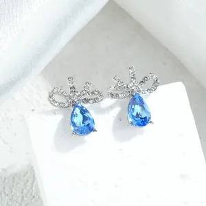 Dettaglio macro di orecchini a fiocco argentati con cristallo blu a goccia per le feste