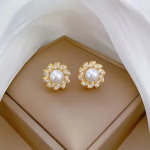 Dettaglio di eleganti orecchini a fiore in oro con perla centrale e petali di zirconi