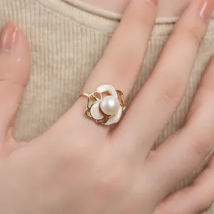 Primo piano di un elegante anello a camelia con petali in smalto bianco e perla