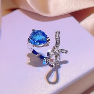 Primo piano di un anello d'argento con pietra a goccia blu e fiocco scintillante