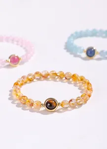 Detailopname van natuurlijke kristallen kralenarmbanden in geel, roze en lichtblauw.