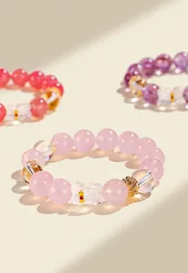 Close-up of pink rose quartz bracelet with clear crystal bear charm and gold accents