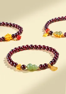 Détail d'un bracelet en perles de grenat avec pendentif gourde en jade Hetian et charms