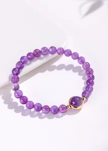 Detailopname van natuurlijke lavendel amethist kralenarmband met goudkleurige steen