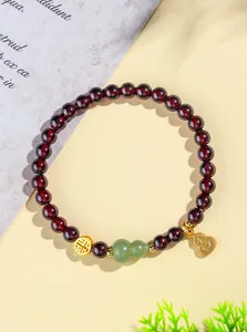 Vue détaillée d'un bracelet en grenat avec gourde en jade vert et breloques dorées.