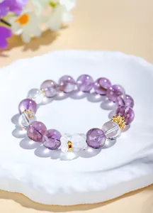 Macro view of clear quartz and amethyst beads with a cute bear charm on a bracelet