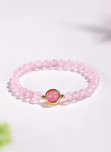 Gedetailleerde close-up van een elegante kralenarmband van roze kwarts met gouden steen.