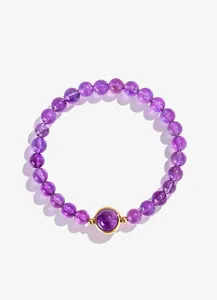 Detailopname van een lila amethist kralenarmband met een goudomrande centrale steen.