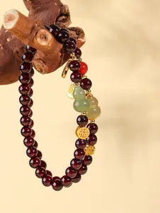 Détail d'un bracelet en perles de grenat avec breloques en jade et accents dorés