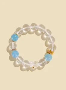 Close-up of a clear white crystal beaded bracelet with blue accents and gold bear charm