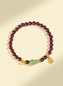 Vue détaillée du bracelet en grenat avec hulu en jade et breloques dorées