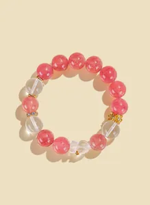 Close-up of a pink and clear quartz crystal beaded bracelet featuring a cute bear charm detail.