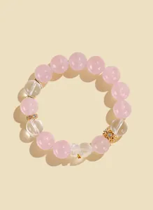 Detailed macro view of a pink rose quartz beaded bracelet with a clear bear charm