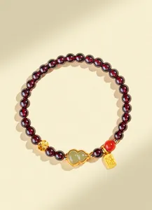 Détail macro du bracelet en perles de grenat avec gourde en jade et breloque dorée Fu