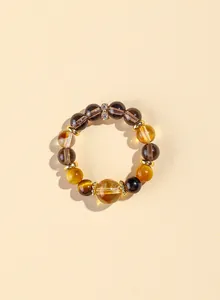 Detailaufnahme eines Naturstein-Armbands mit Tigerauge, gelbem Kristall und Goldakzenten