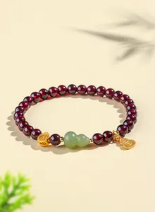 Vue détaillée d'un bracelet en grenat avec gourde en jade et breloques dorées