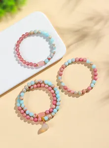 Nahaufnahme von Naturstein-Armbändern aus Rhodonit und Achat mit Lotus-Anhänger
