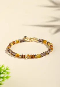 Detailansicht eines Armbands aus natürlichen Tigeraugen- und Kristallperlen mit Gold.