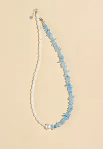 Detailed view of aquamarine chip beads and white pearl on a delicate necklace