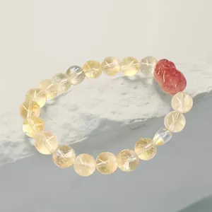 Vue détaillée d'un bracelet en citrine jaune avec une perle rouge sculptée